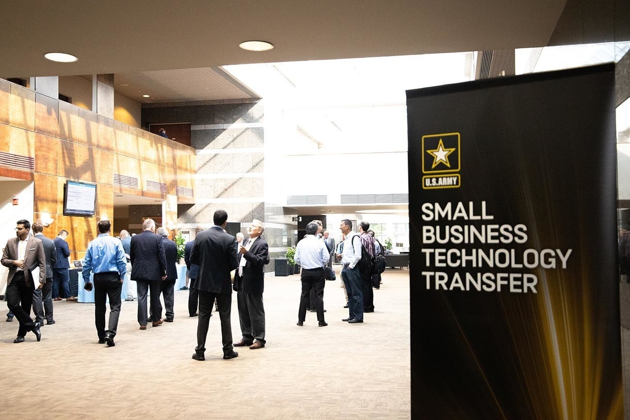Participants talking beside a U.S. Army Small Business Technology Transfer sign at an industry day