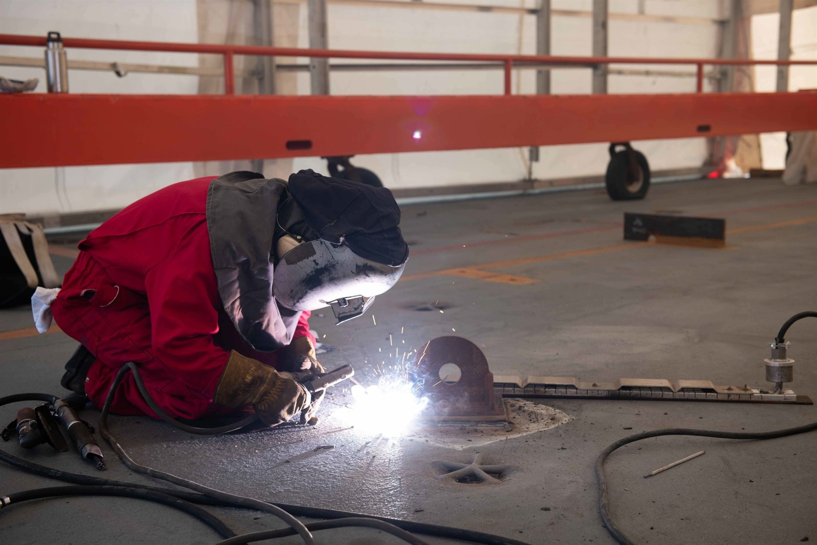 A Newport News Shipbuilding contractor welding a strongback aboard an aircraft carrier.